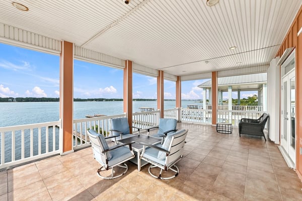 Covered waterfront porch with lounge chairs, tile flooring, and expansive bay views