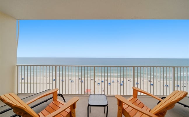 Gulf-view balcony with two Adirondack chairs looking out over the white sand beach